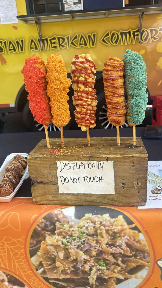 Five colorful Korean corn dogs displayed in front of the food truck