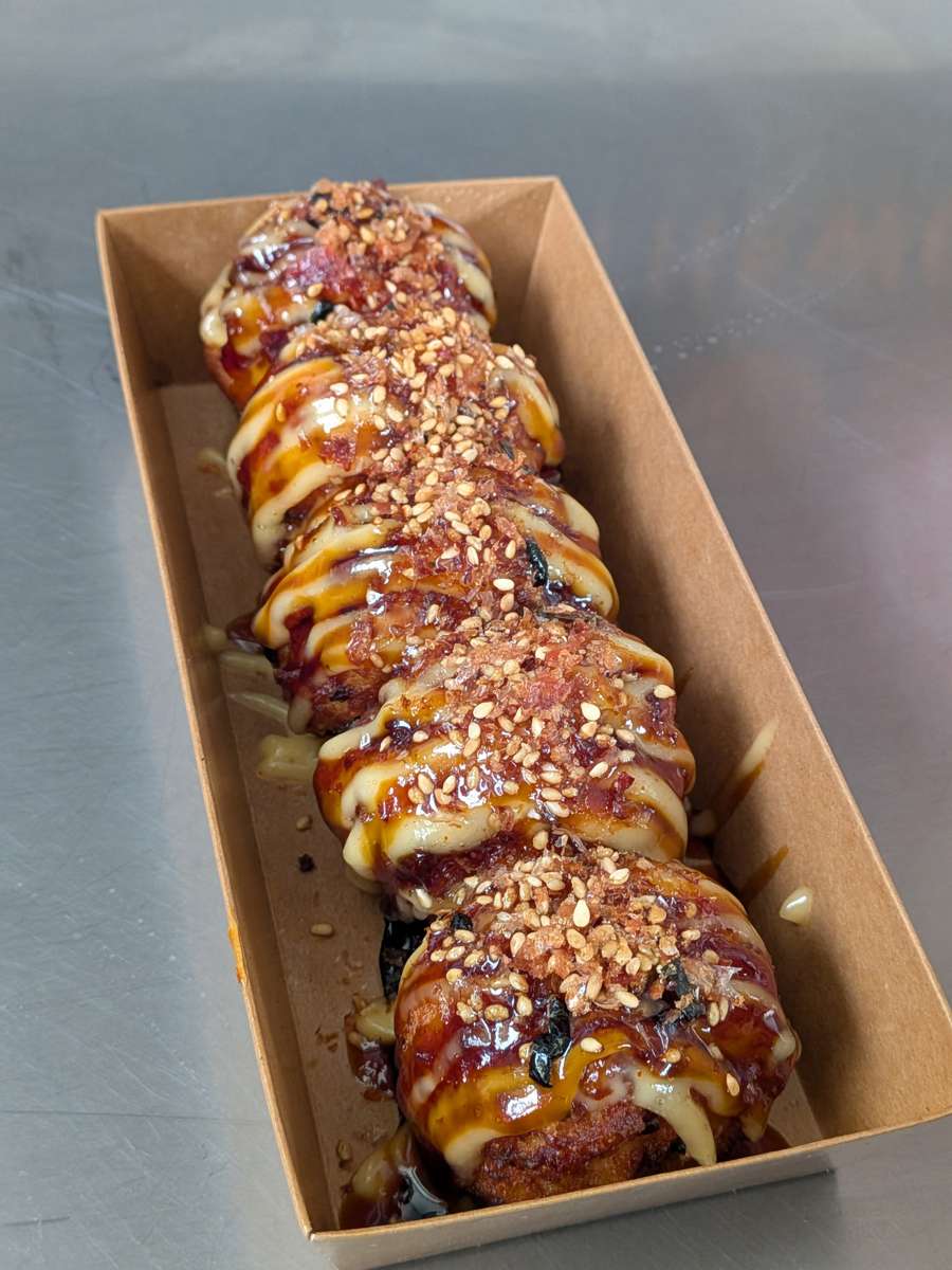 Five golden Wokaroni and Cheese pieces with sauce and sesame seeds